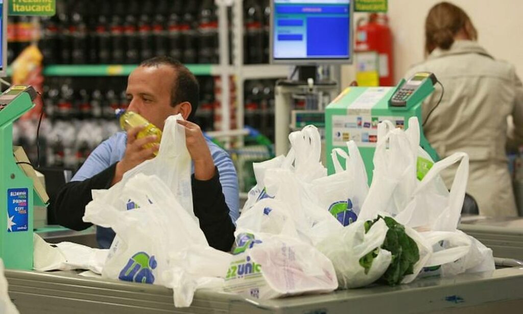 Na imagem aparece um homem trabalhando em um caixa de supermercado. Representando a nova ação